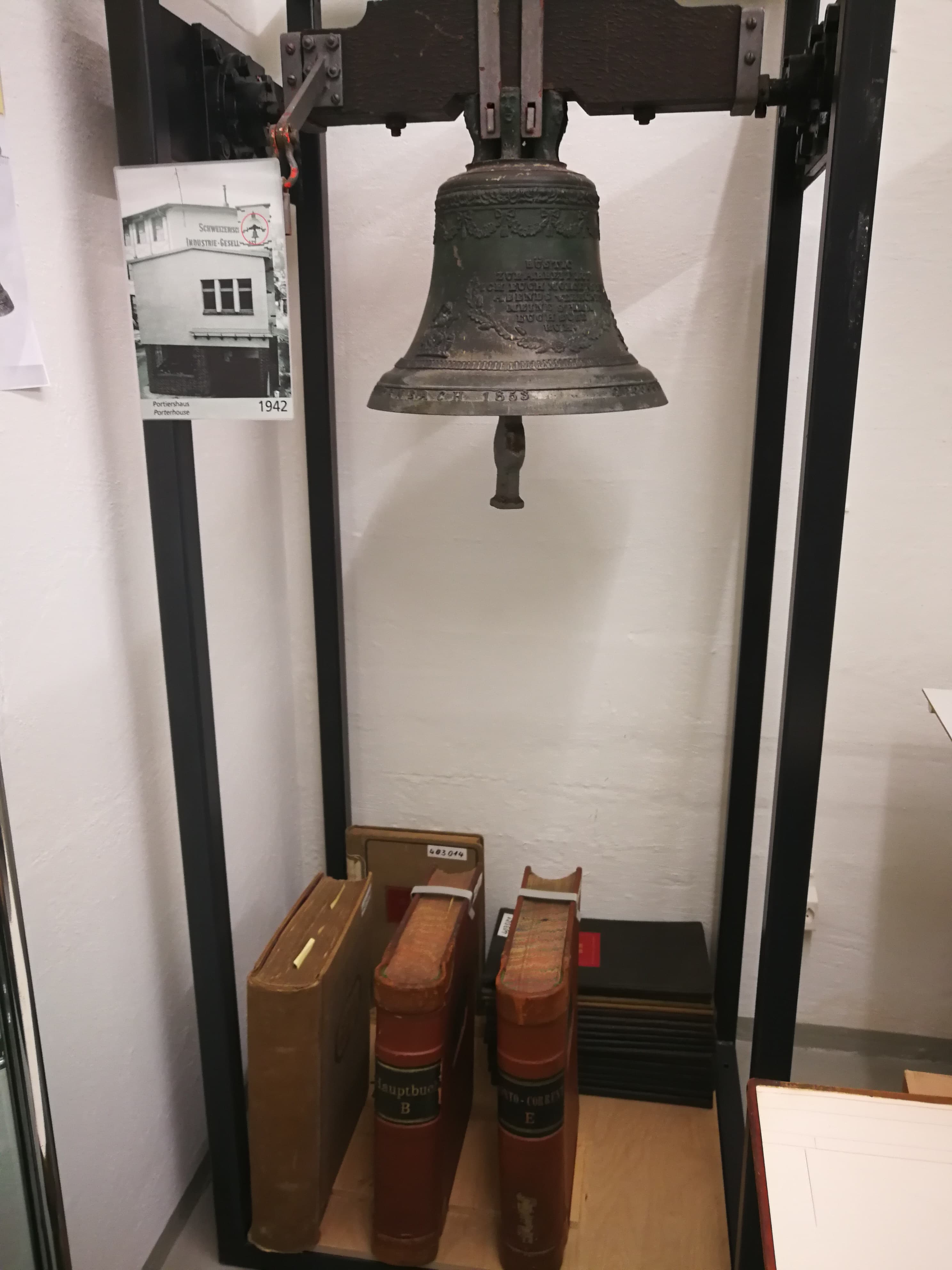 Die Glocke, die die Arbeiter jeden Morgen empfing. Unten riesige Kassenbücher. In Relation gebracht: Die Glocke allein ist gut über einen halben Meter lang.
