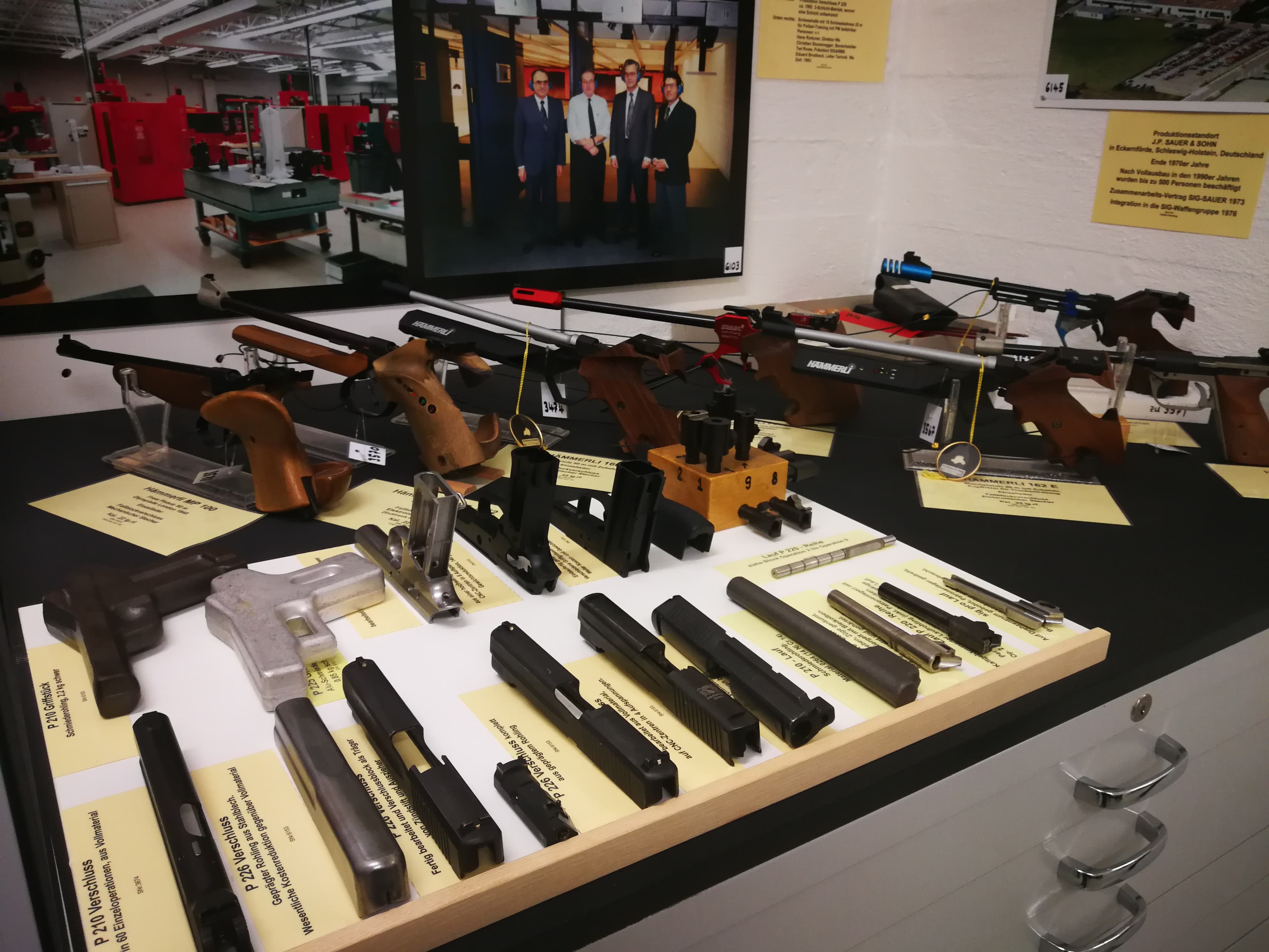 Verschiedene Hämmerli-Sportpistolen im Hintergrund, sowie Arbeitsschritte in der Produktion einer P226.
