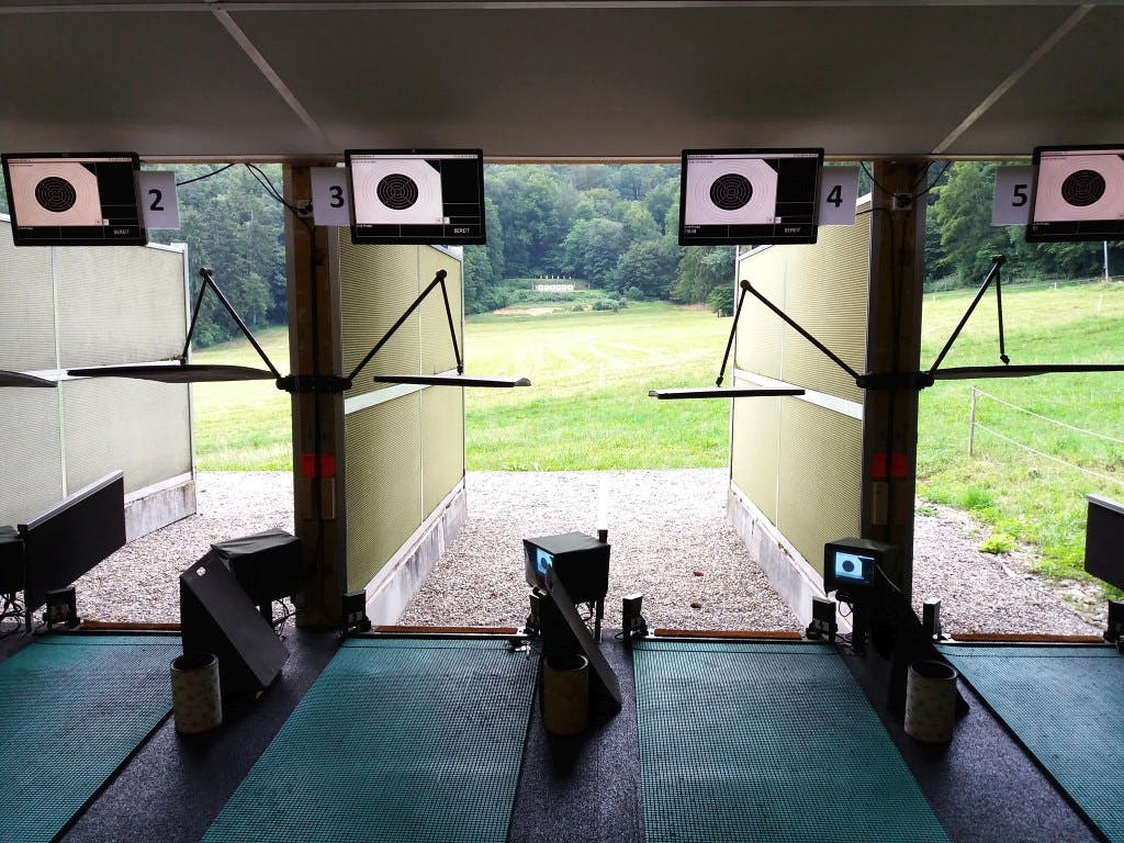 Freie Läger, bereit für Schützen. Schallschutzwändetrennen jeweils zwei Läger vom Rest ab. Die Monitore oben zeigen das Trefferbild des kleinen Monitors beim Schützen - eine Massnahme, damit neugierige Zuschauer den armen Warner beim Blickerhaschen auf den kleinen Monitor nicht bedrängen.